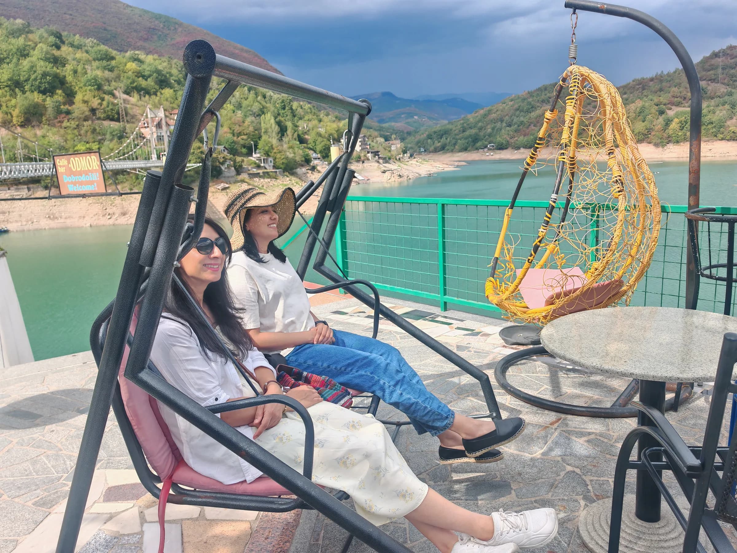 Sisters relaxing on swing seats at a lakeside café