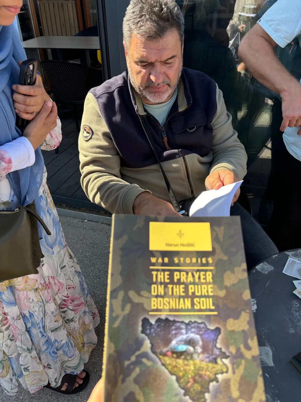 A local guide sharing a book of stories from the war