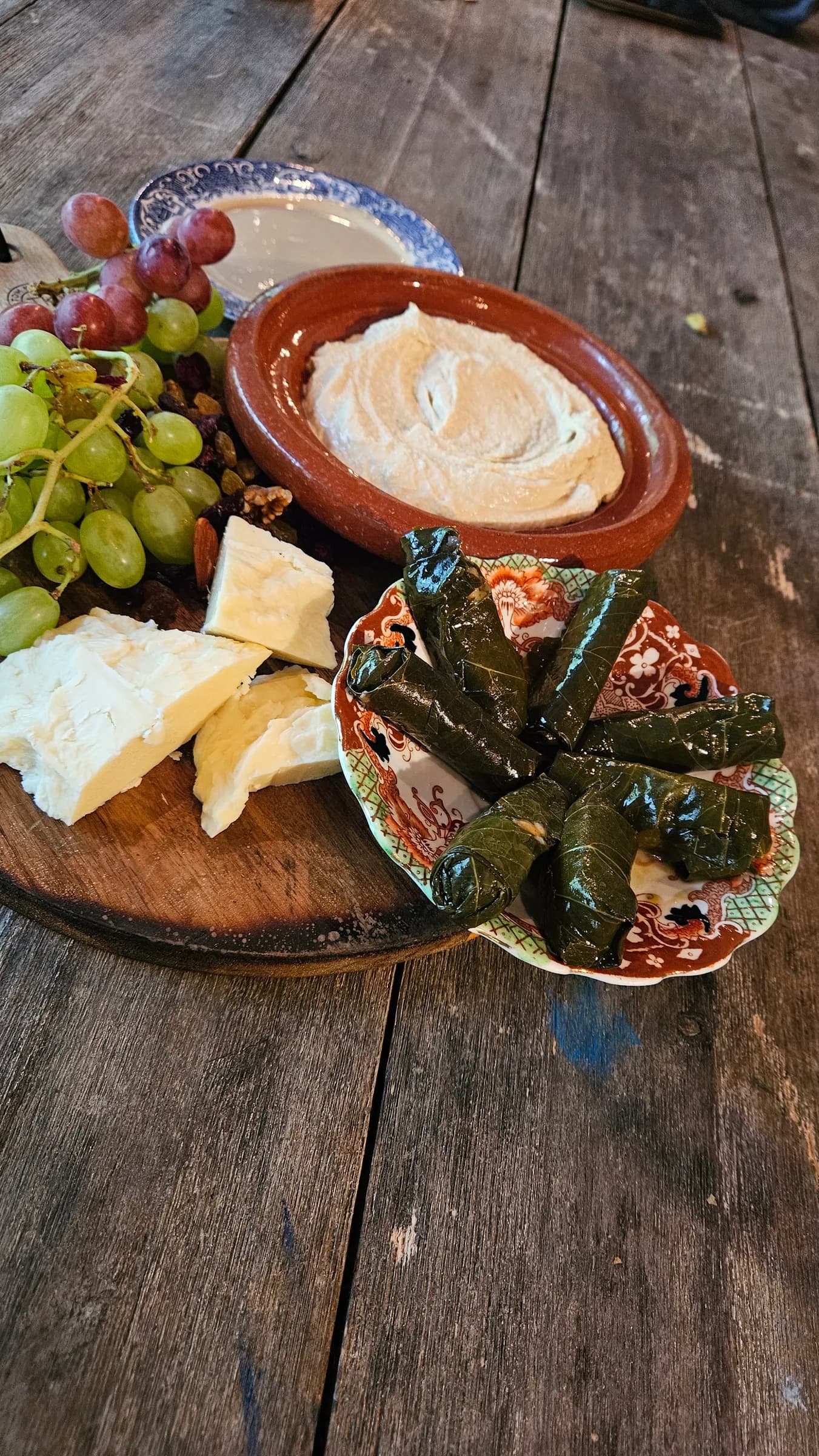 Breakfast spread with grapes, hummus, cheese and stuffed vine leaves