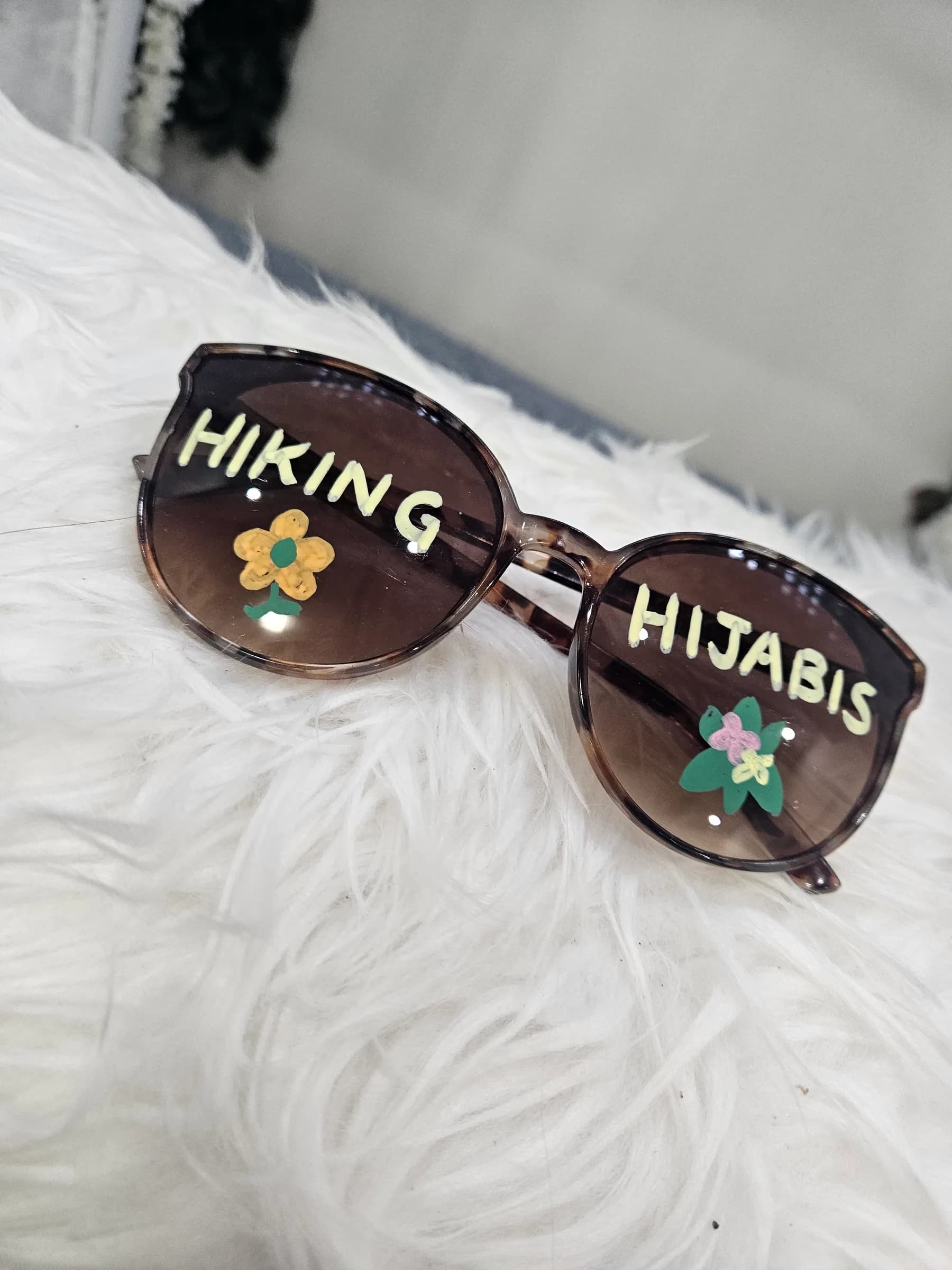 Hiking Hijabis sunglasses on a fluffy white throw