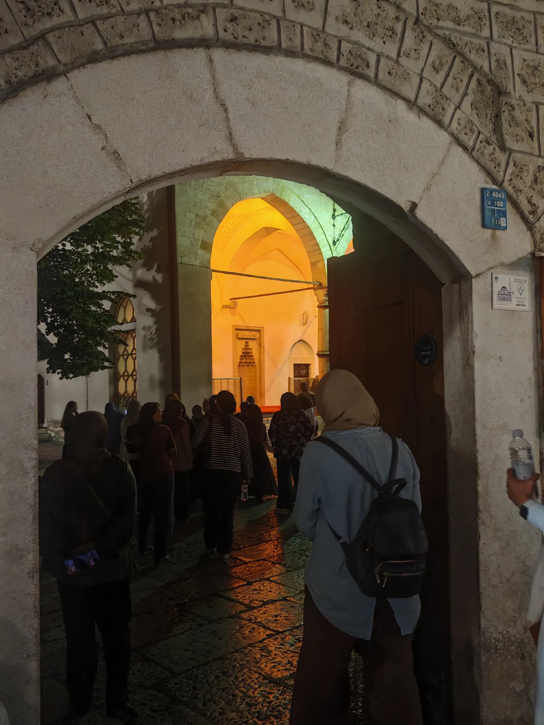 Sisters walking through an archway into a mosque courtyard at night