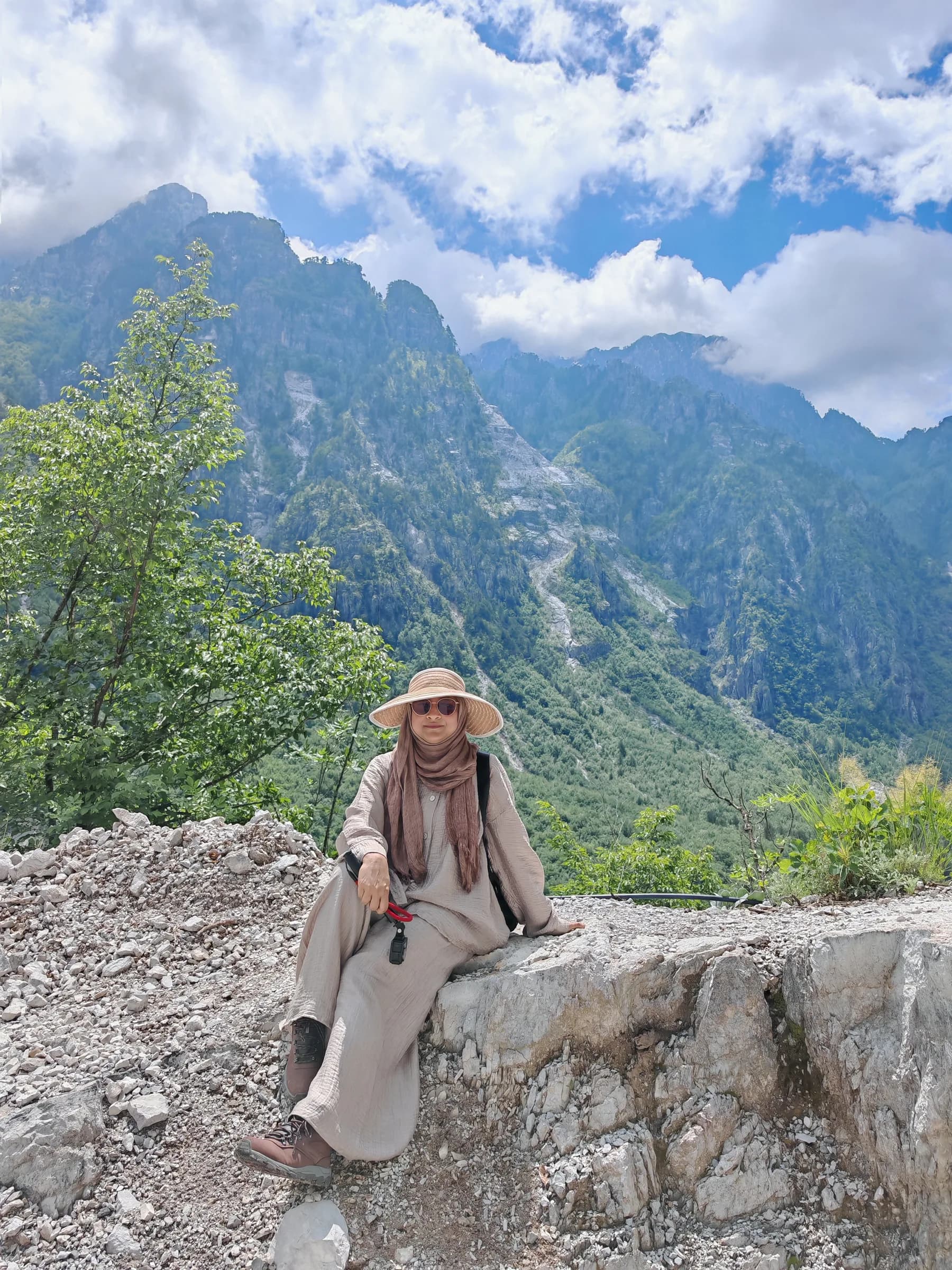 A sister resting on a rock with mountains behind