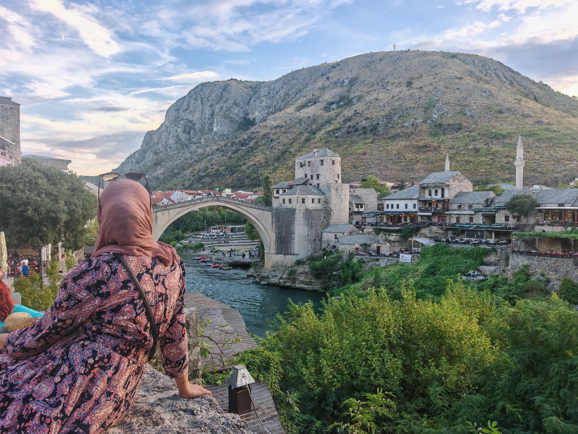 A sister sitting above the Neretva with Mostar's Old Bridge behind