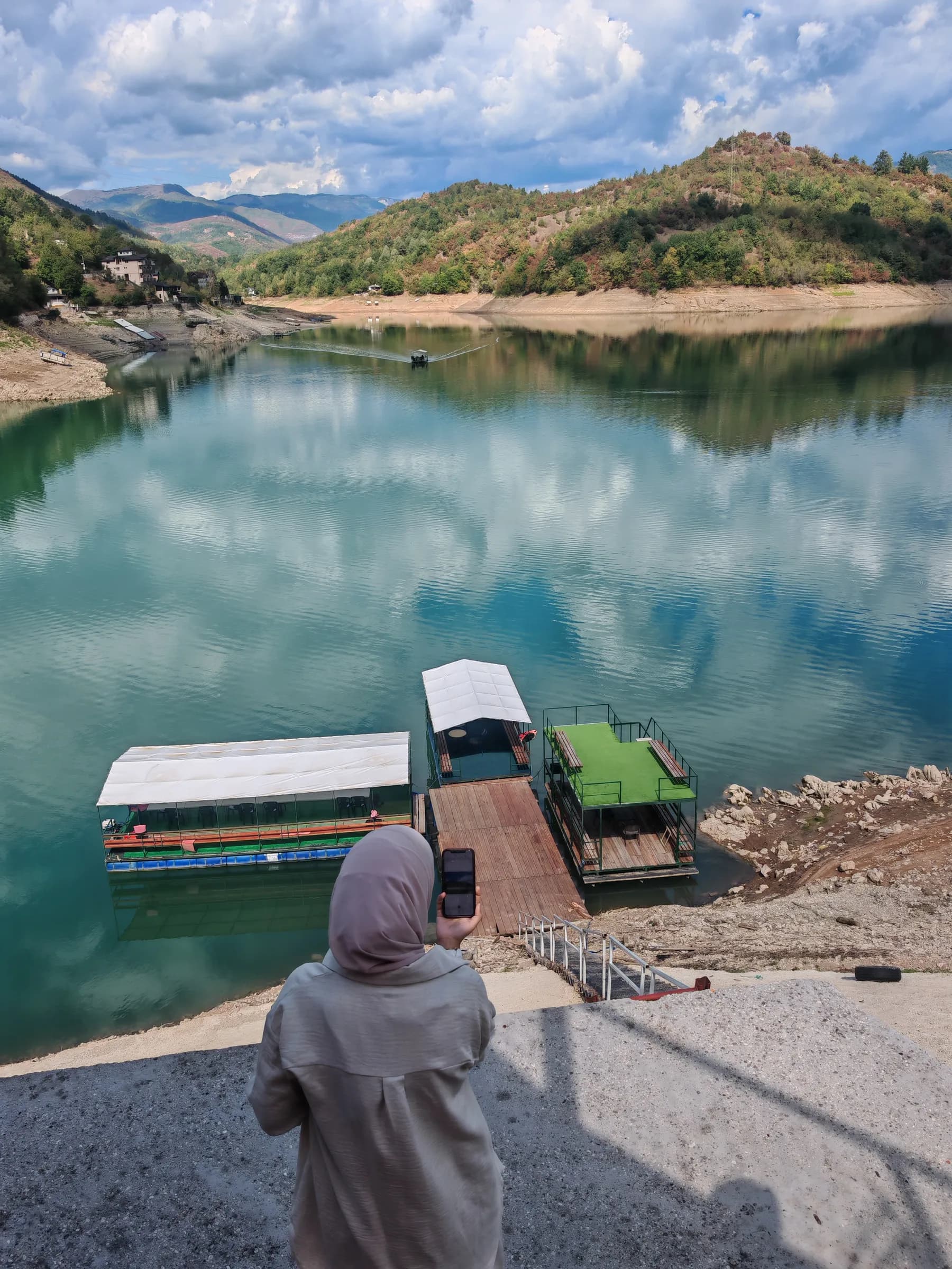 A sister looking out over Jablanica Lake towards moored boats