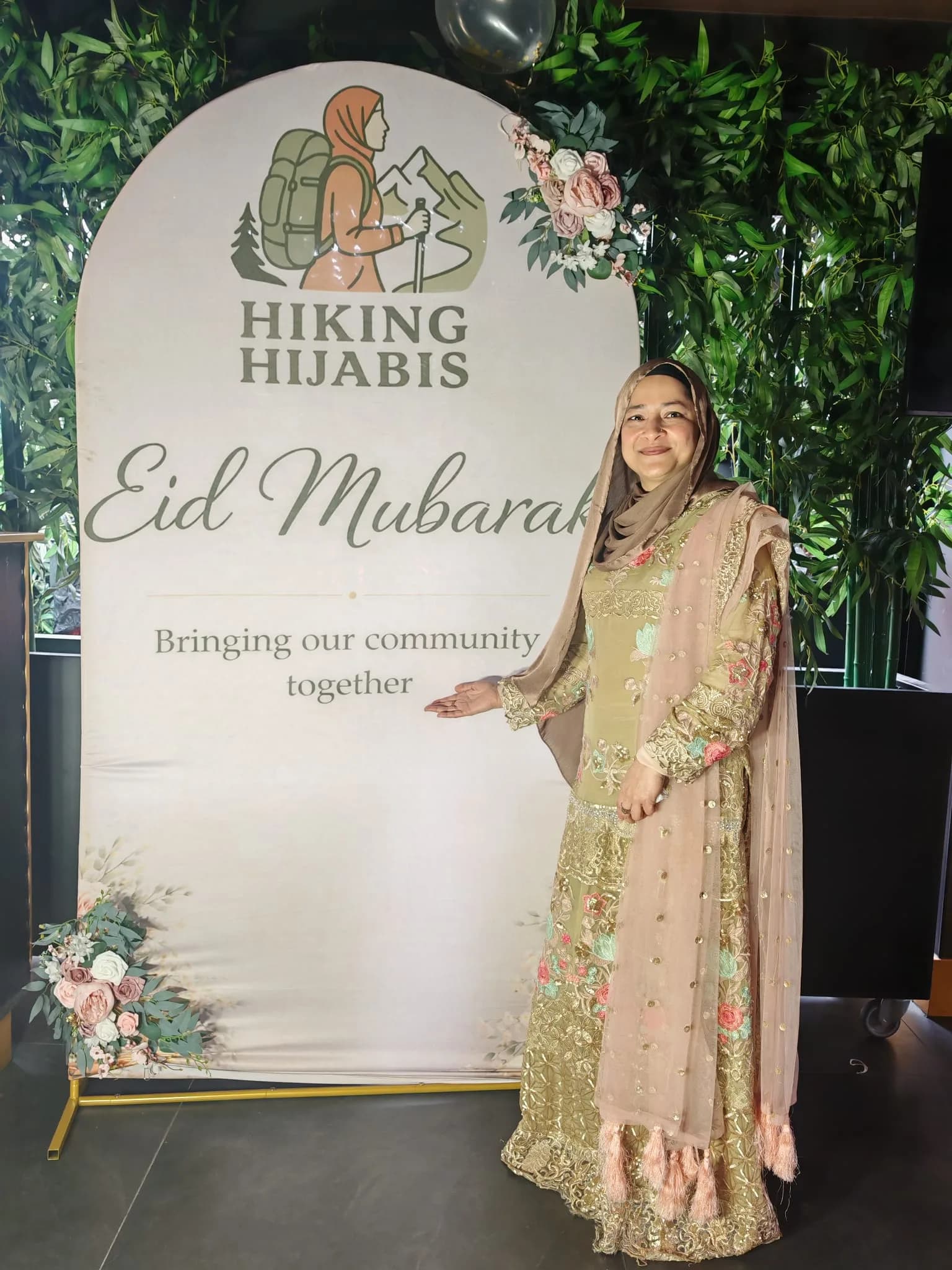 A sister by the Eid Mubarak board reading: bringing our community together