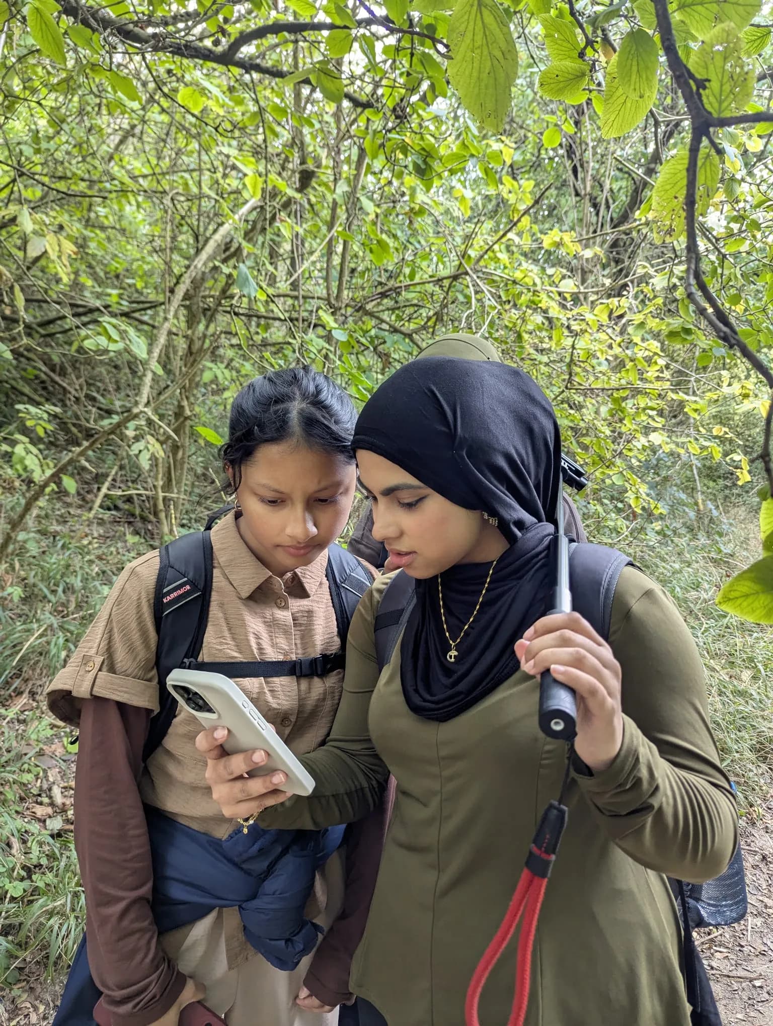 Two sisters checking the route on a phone in the woods