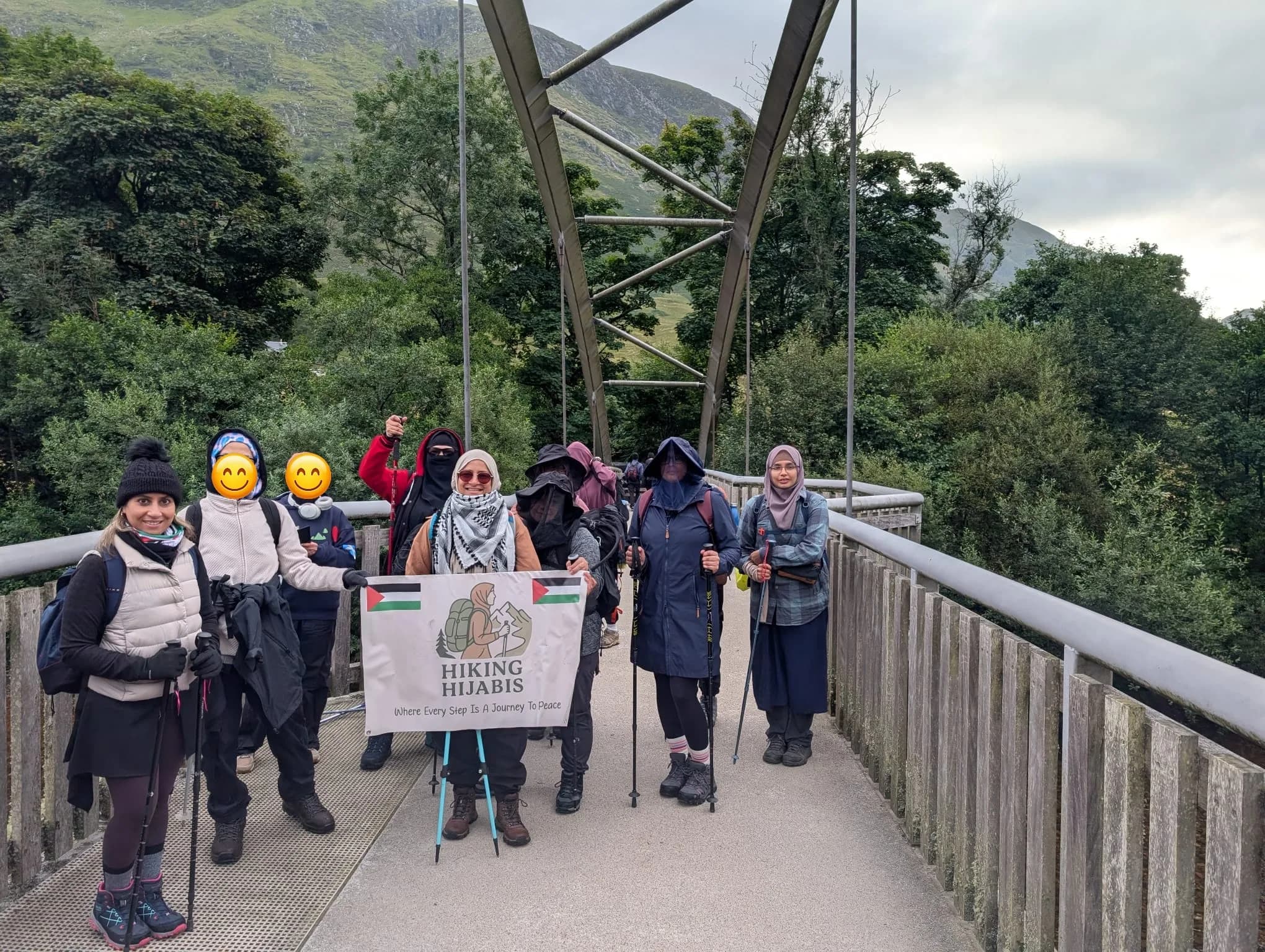 The group with the Hiking Hijabis banner on a footbridge below the mountains