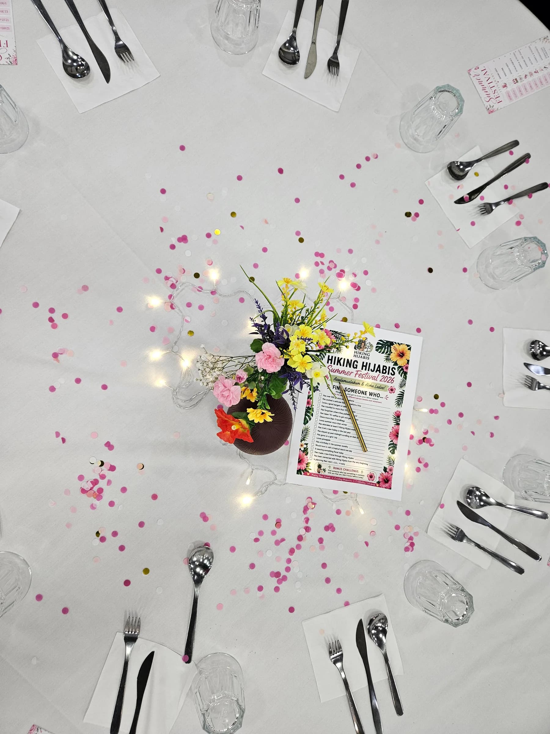 A table set with confetti, flowers and the festival programme